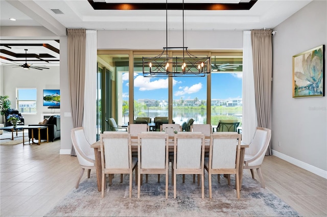 dining space featuring tile patterned flooring, ceiling fan with notable chandelier, visible vents, baseboards, and a raised ceiling