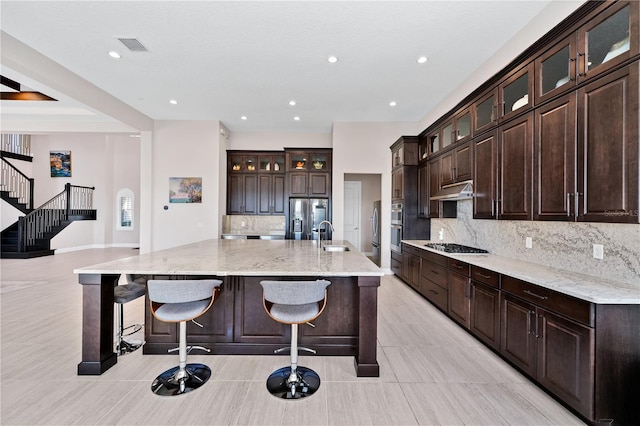 kitchen with appliances with stainless steel finishes, a kitchen bar, a spacious island, and tasteful backsplash