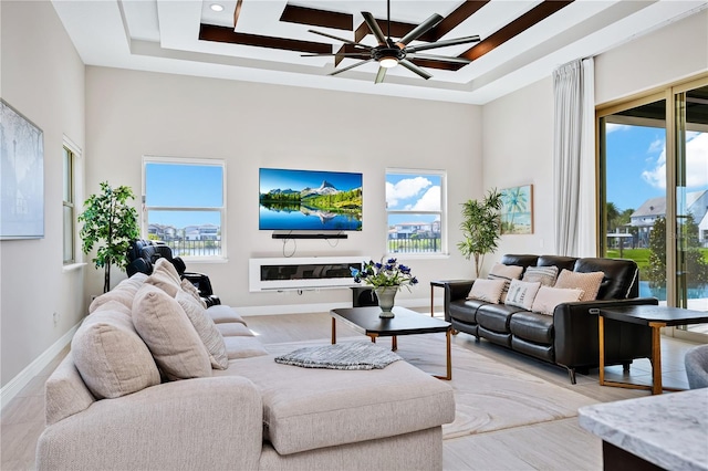 living room featuring a tray ceiling, plenty of natural light, and a high ceiling