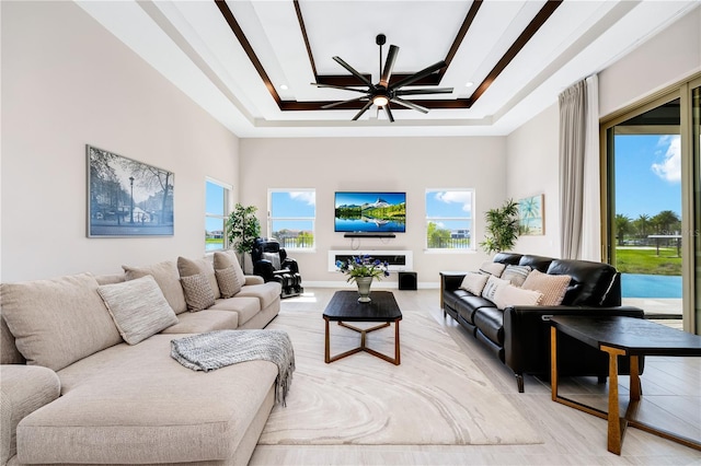 living room featuring ceiling fan, a high ceiling, and a tray ceiling