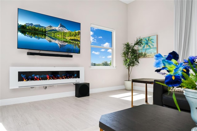 living area featuring a glass covered fireplace and baseboards