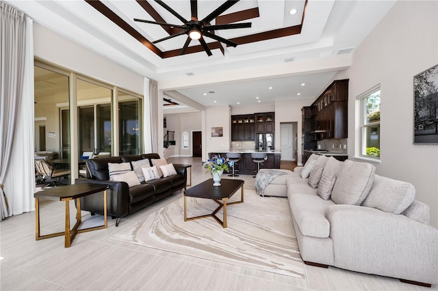 living room featuring a tray ceiling, a ceiling fan, indoor wet bar, and recessed lighting