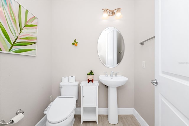 half bathroom featuring a sink, toilet, and baseboards