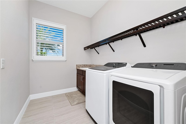 washroom featuring washer and dryer, cabinet space, baseboards, and light tile patterned floors