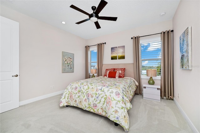 bedroom featuring light colored carpet, ceiling fan, and baseboards