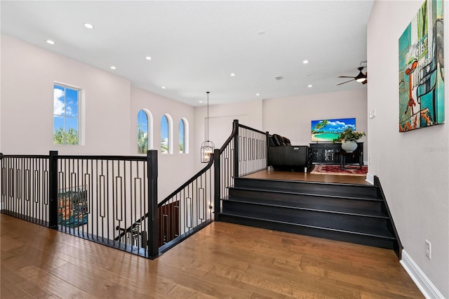 stairway featuring baseboards, ceiling fan, wood finished floors, and recessed lighting