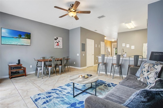 living room featuring a ceiling fan, light tile patterned flooring, visible vents, and baseboards