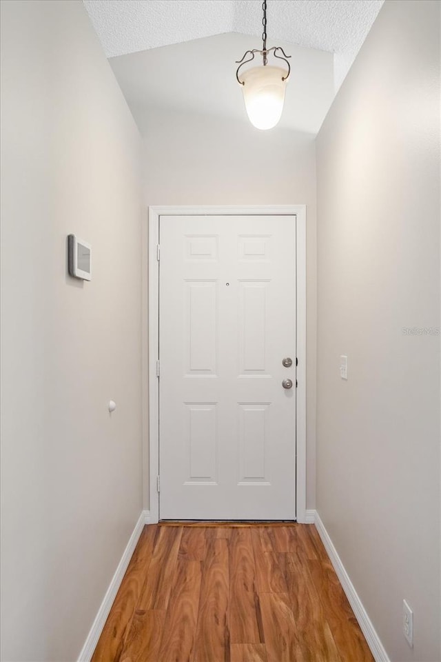 doorway featuring a textured ceiling, light wood-type flooring, and baseboards