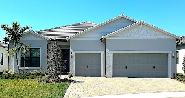 ranch-style house with a garage, a tiled roof, decorative driveway, and stucco siding