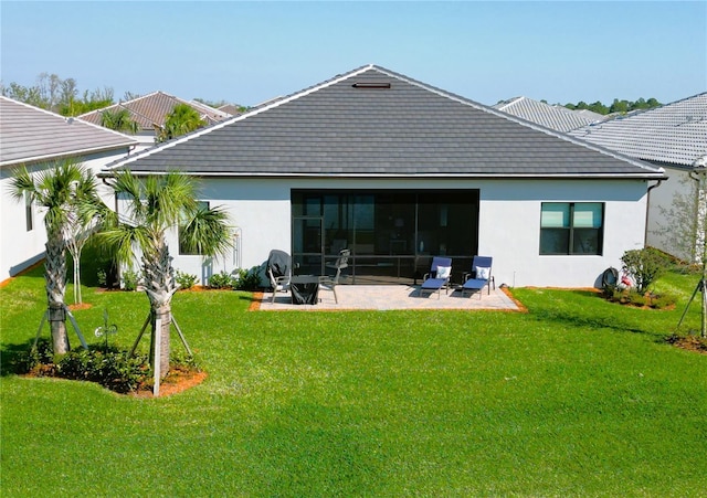 back of property with stucco siding, a lawn, a sunroom, and a patio