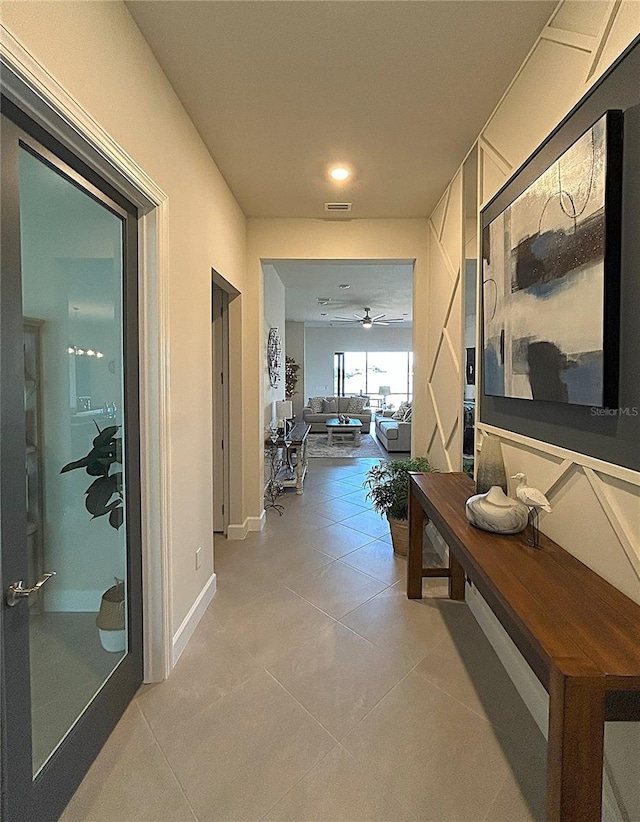 hallway featuring visible vents, baseboards, and light tile patterned floors