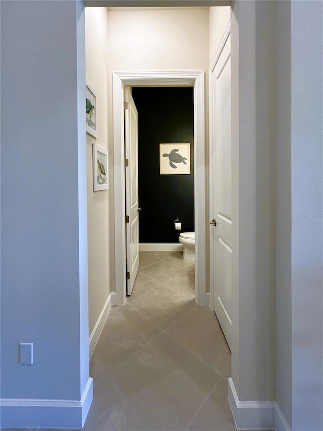 hall featuring baseboards and light tile patterned floors