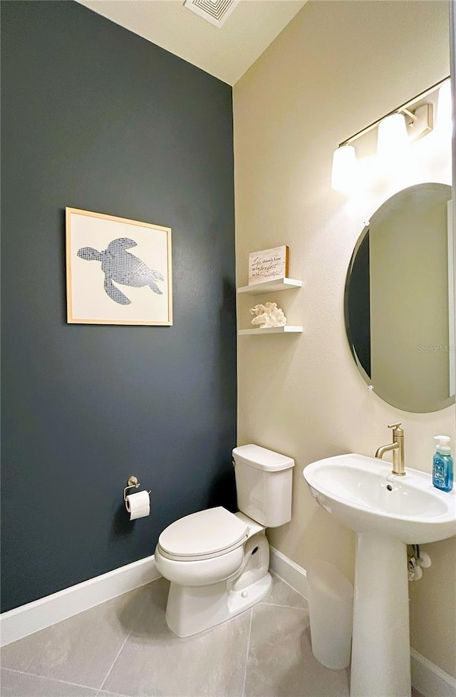 half bath featuring baseboards, a sink, toilet, and tile patterned floors