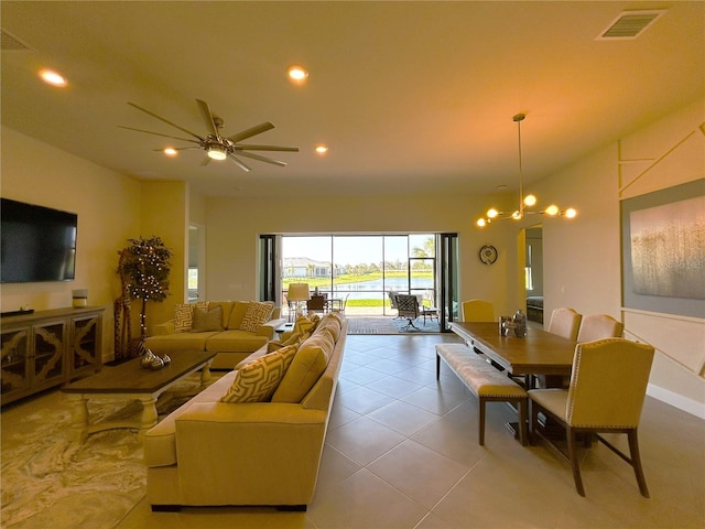 tiled living area with ceiling fan with notable chandelier, a water view, visible vents, and recessed lighting