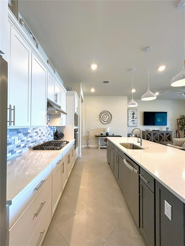 kitchen featuring visible vents, appliances with stainless steel finishes, a sink, under cabinet range hood, and backsplash