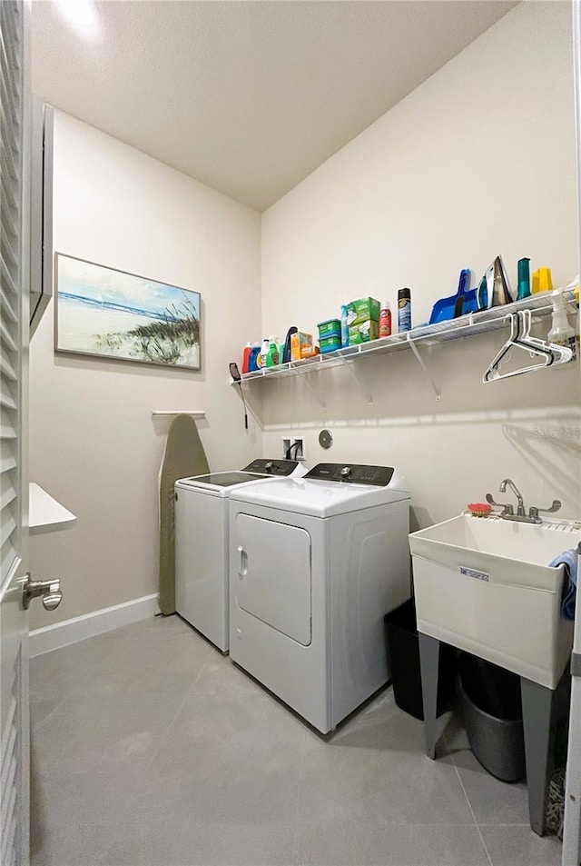 clothes washing area featuring laundry area, baseboards, washing machine and clothes dryer, and light tile patterned flooring