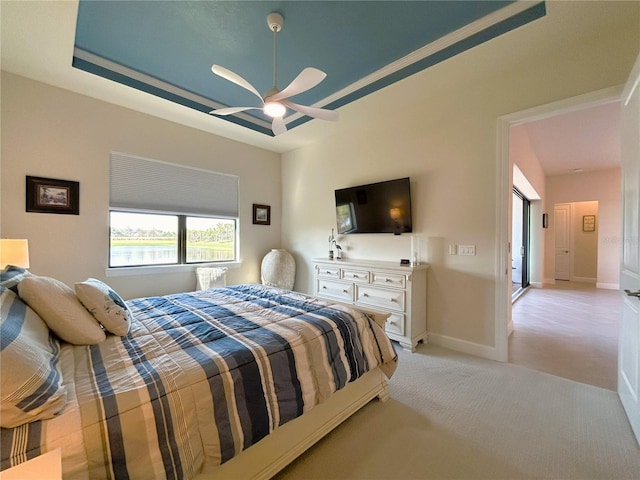 bedroom with baseboards, a tray ceiling, a ceiling fan, and light colored carpet