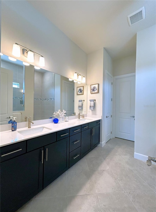 bathroom featuring double vanity, a sink, visible vents, and baseboards