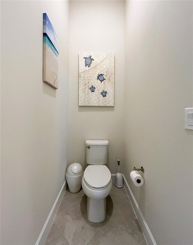 bathroom with toilet, baseboards, and tile patterned floors