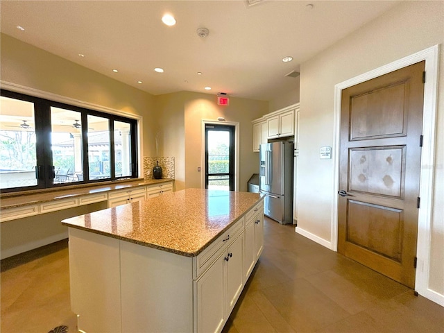 kitchen with a kitchen island, light stone countertops, white cabinetry, high end fridge, and recessed lighting