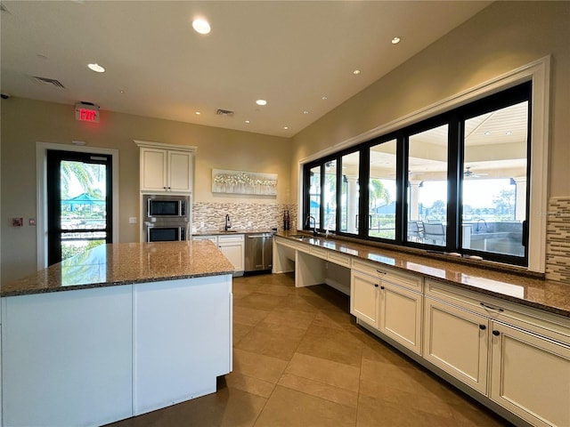 kitchen featuring backsplash, appliances with stainless steel finishes, dark stone counters, and a sink