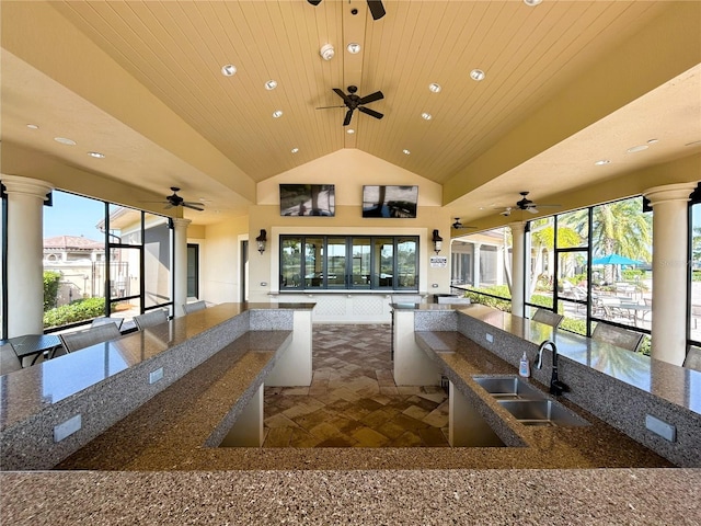 kitchen with open floor plan, wooden ceiling, a sink, and dark stone countertops