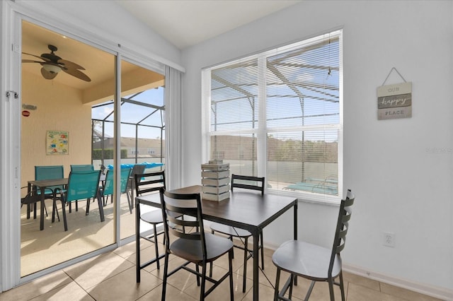 dining space featuring a ceiling fan, a sunroom, baseboards, and light tile patterned floors