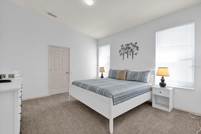 bedroom with lofted ceiling, multiple windows, visible vents, and light colored carpet