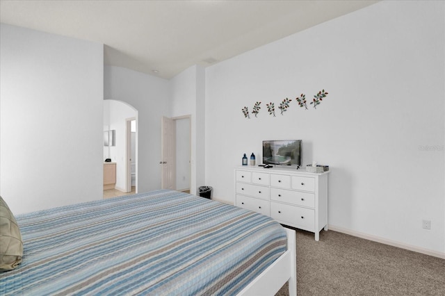 bedroom with arched walkways, light colored carpet, and baseboards