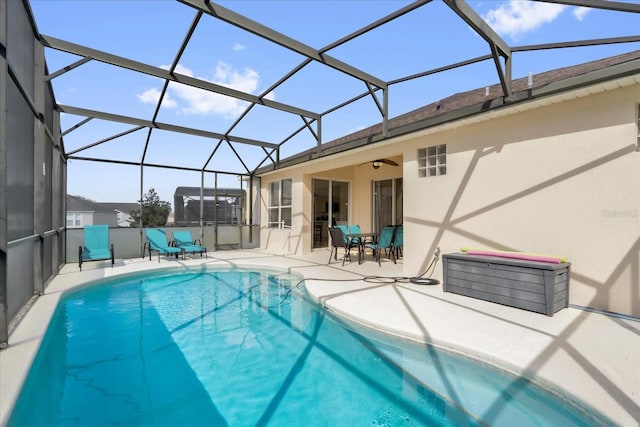 view of swimming pool featuring a fenced in pool, glass enclosure, a patio area, and ceiling fan