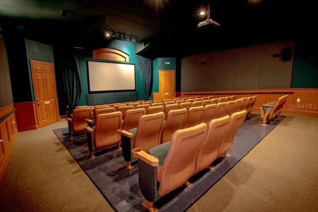 carpeted home theater with wainscoting, a decorative wall, and track lighting