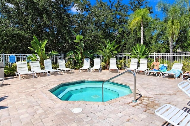 view of swimming pool with a patio, fence, and a hot tub