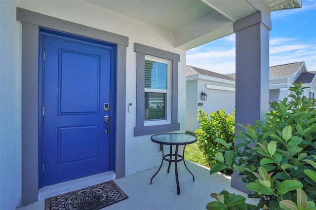 entrance to property featuring an attached garage and stucco siding