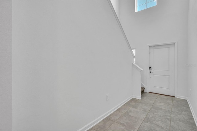 interior space featuring stairs, a towering ceiling, and baseboards