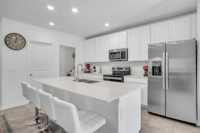 kitchen featuring appliances with stainless steel finishes, white cabinetry, a sink, and light tile patterned floors