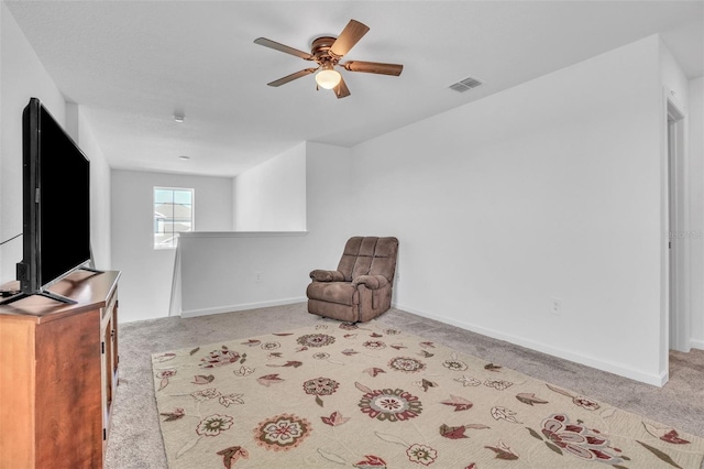 living area with light carpet, baseboards, visible vents, and ceiling fan