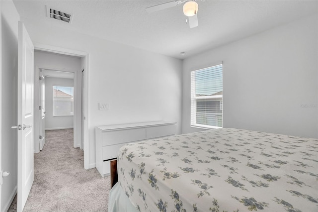 bedroom featuring ceiling fan, visible vents, baseboards, and light colored carpet