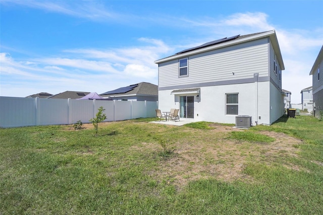 rear view of house with solar panels, a patio, a fenced backyard, a yard, and central air condition unit