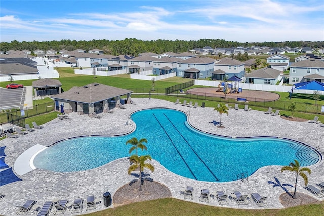 community pool with a residential view, fence, and a yard