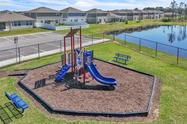 community playground featuring a yard, a residential view, a water view, and fence