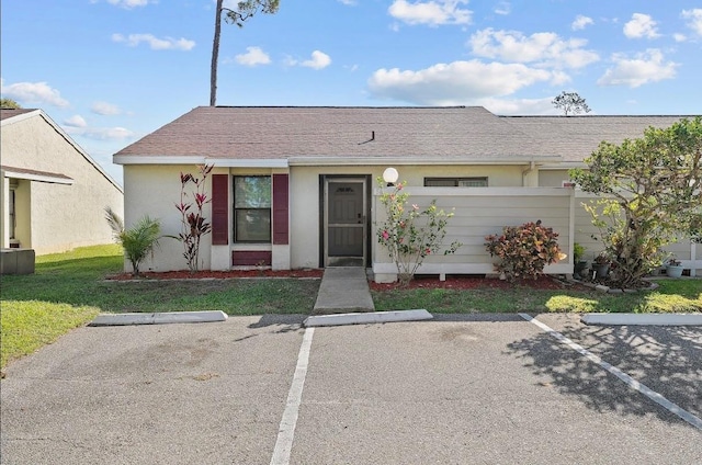 view of front of home featuring a front yard, uncovered parking, fence, and stucco siding