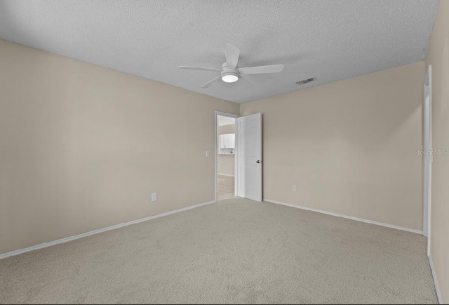 unfurnished room with carpet floors, visible vents, a ceiling fan, a textured ceiling, and baseboards