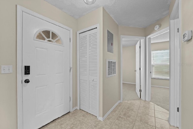 foyer featuring light tile patterned floors, visible vents, baseboards, and a textured ceiling