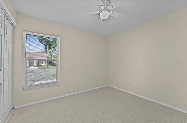 empty room featuring light colored carpet, a textured ceiling, and baseboards