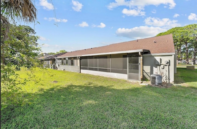 back of house featuring a sunroom, central AC, and a lawn