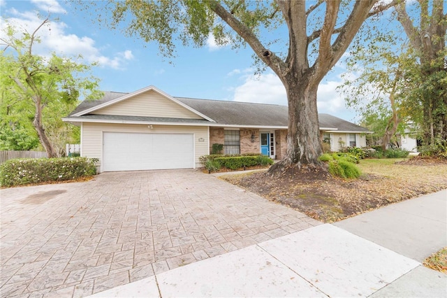 single story home with a garage, brick siding, decorative driveway, and fence