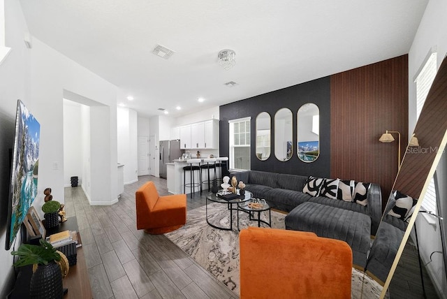 living room featuring light wood-style floors, baseboards, visible vents, and recessed lighting