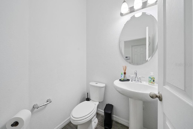 bathroom featuring toilet, a sink, baseboards, and wood finished floors