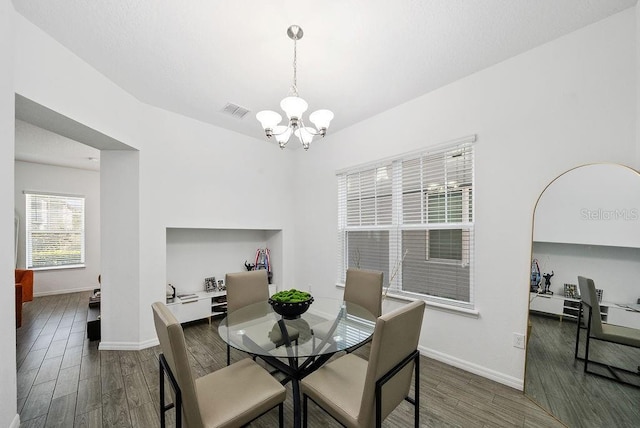 dining area featuring baseboards, visible vents, a chandelier, and dark wood-type flooring