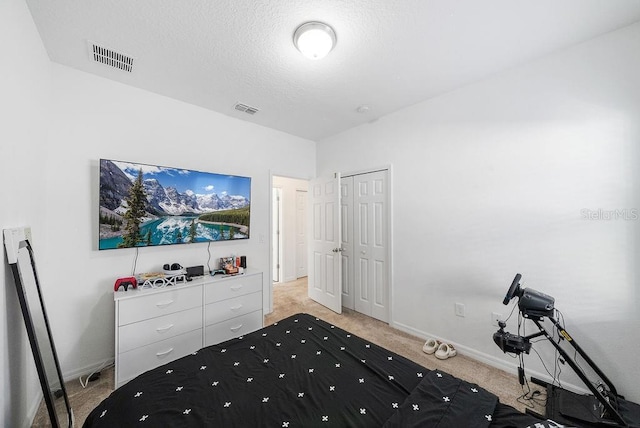 bedroom featuring visible vents, a textured ceiling, and light colored carpet